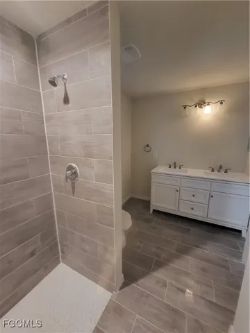 a bathroom with a double vanity sink a toilet and a shower