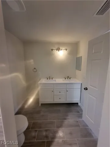 a bathroom with a double vanity sink mirror and toilet