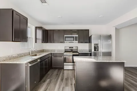 a kitchen with stainless steel appliances granite countertop a stove a sink and a refrigerator