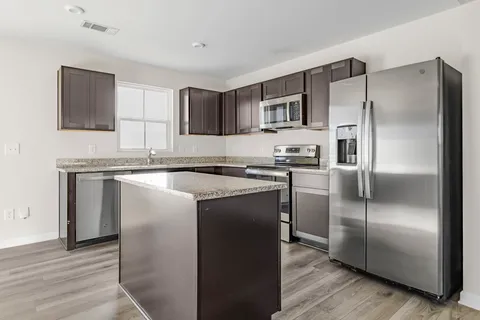 a kitchen with stainless steel appliances granite countertop a refrigerator and a stove top oven