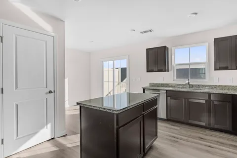 a kitchen with kitchen island granite countertop a sink stove and refrigerator