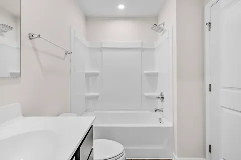 a bathroom with a bathtub shower sink vanity and toilet