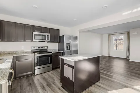 a kitchen with stainless steel appliances granite countertop a stove a sink dishwasher a refrigerator and a microwave oven with wooden floor