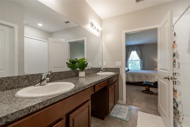 a en suite bathroom with a granite countertop sink and a mirror