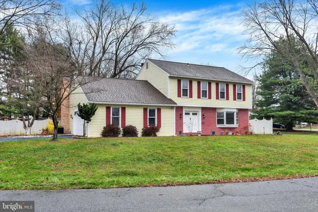a view of a white house with a big yard and large trees