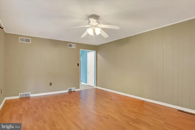 an empty room with wooden floor ceiling fan and windows