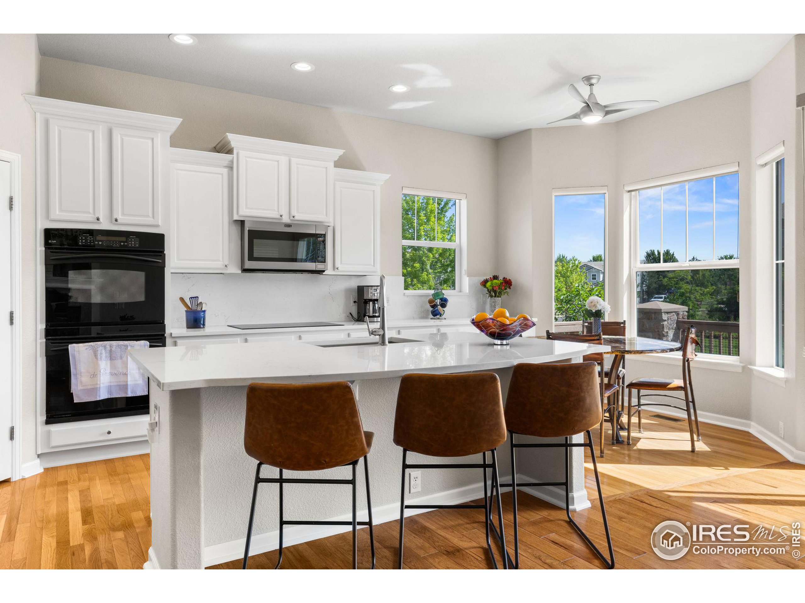 a open kitchen with stainless steel appliances granite countertop a stove top oven a sink a dining table and chairs