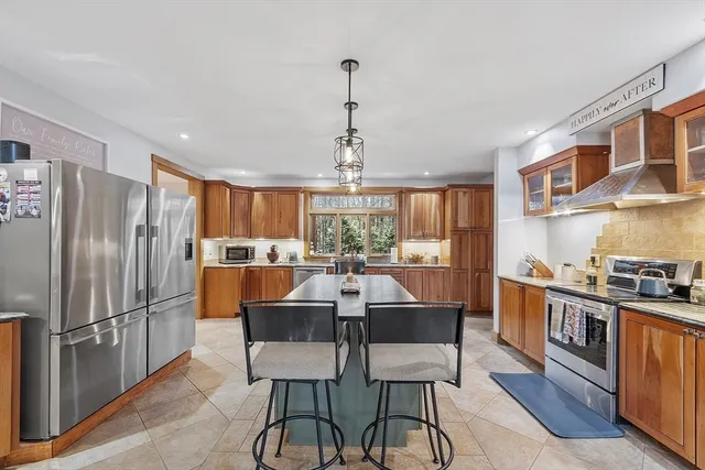 a kitchen with stainless steel appliances granite countertop a dining table chairs refrigerator and cabinets