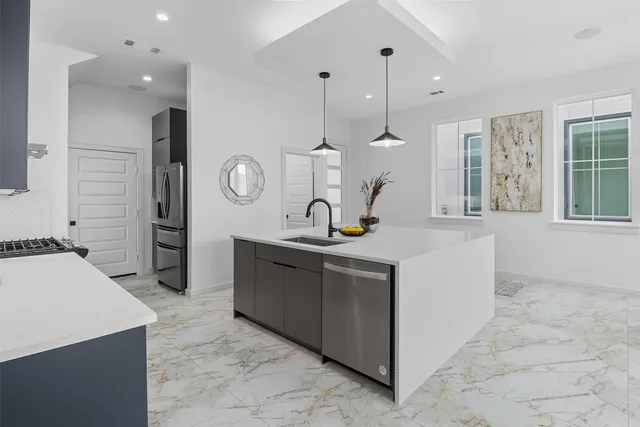 a kitchen with stainless steel appliances kitchen island granite countertop a sink a stove and a wooden floors