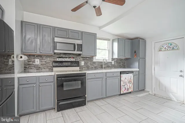 a kitchen with granite countertop white cabinets stainless steel appliances a sink and a window