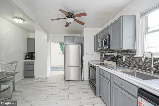 a kitchen with stainless steel appliances granite countertop a refrigerator a stove a sink a oven with a dining table and chairs