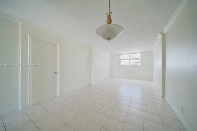 a view of an empty room with a window and a chandelier fan