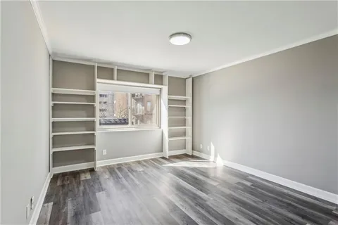 a view of an empty room with a window and wooden floor