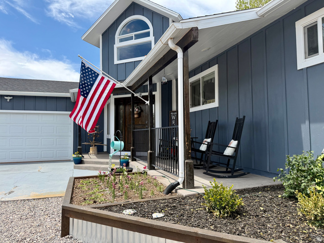 656 South Bullion Canyon Road Marysvale, UT 84750 - Photo 54 of 57 Exterior featuring a board-and-batten facade in a deep blue hue, a white paneled garage door, and a covered front porch