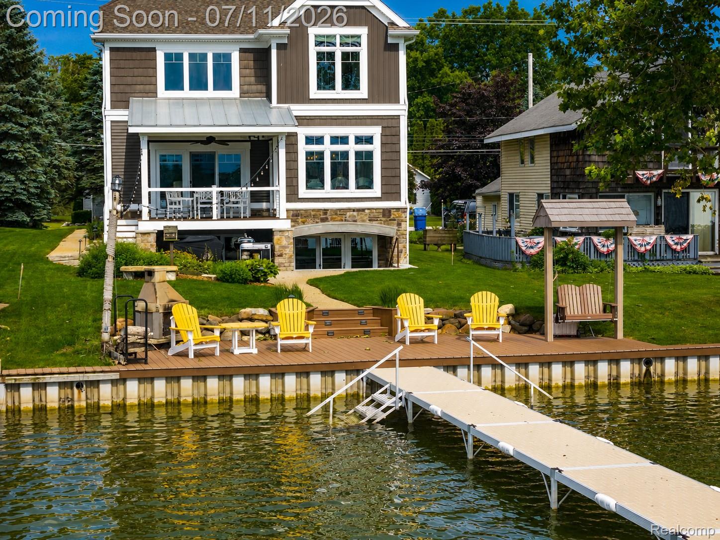 12033 Torrey Road Fenton, MI 48430 - Photo 8 of 51 Waterfront property featuring a private boat dock, expansive backyard with manicured lawn, and a multi-level deck with a covered patio