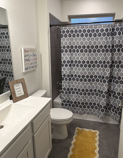 2016 Wooded Run Trail Georgetown, TX 78628 - Photo 13 of 16 Bathroom featuring a white vanity with an integrated sink, dark gray large-format tile flooring, a shower-over-tub with dark gray tile surround, and an upper transom window