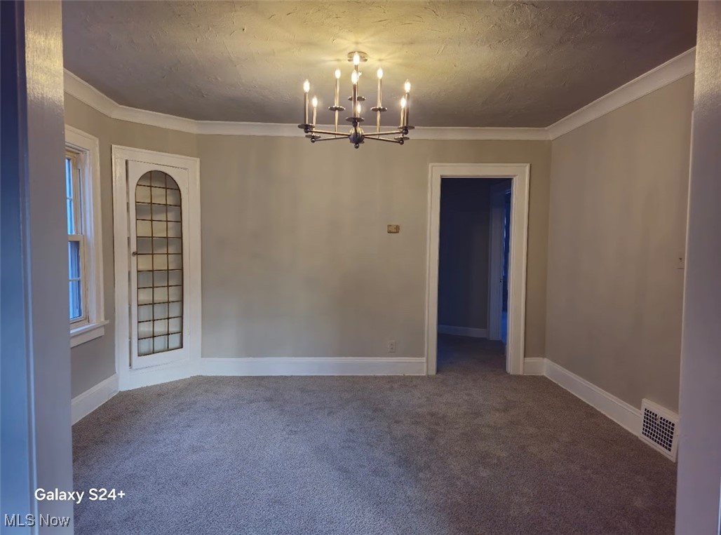 3571 Riedham Road Cleveland, OH 44120 - Photo 7 of 24 Empty room with carpet, a textured ceiling, crown molding, and an inviting chandelier