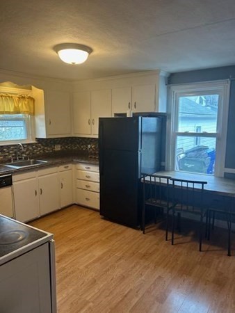 179 Powell Avenue Springfield, MA 01118 - Photo 10 of 30 a kitchen with granite countertop a refrigerator a stove a sink dishwasher and wooden cabinets with wooden floor