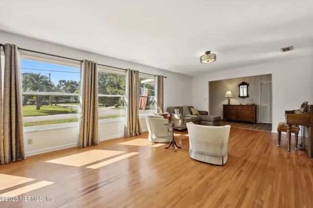 a living room with furniture a large window and wooden floor