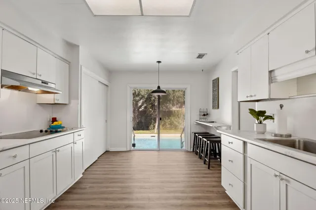 a kitchen with stainless steel appliances granite countertop a sink cabinets and wooden floor