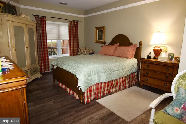 a bedroom with a bed a dresser and next to a window