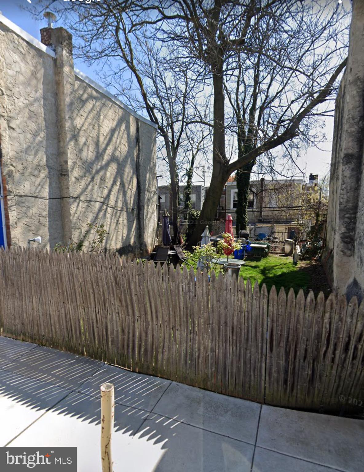 a view of a backyard with wooden fence and a large tree