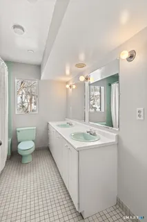 a spacious bathroom with a granite countertop sink a toilet a mirror and shower