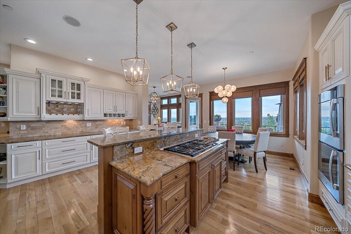 1254 Buffalo Ridge Road Castle Pines, CO 80108 - Photo 14 of 40 a kitchen with granite countertop a stove a sink a kitchen island with chairs and wooden floor