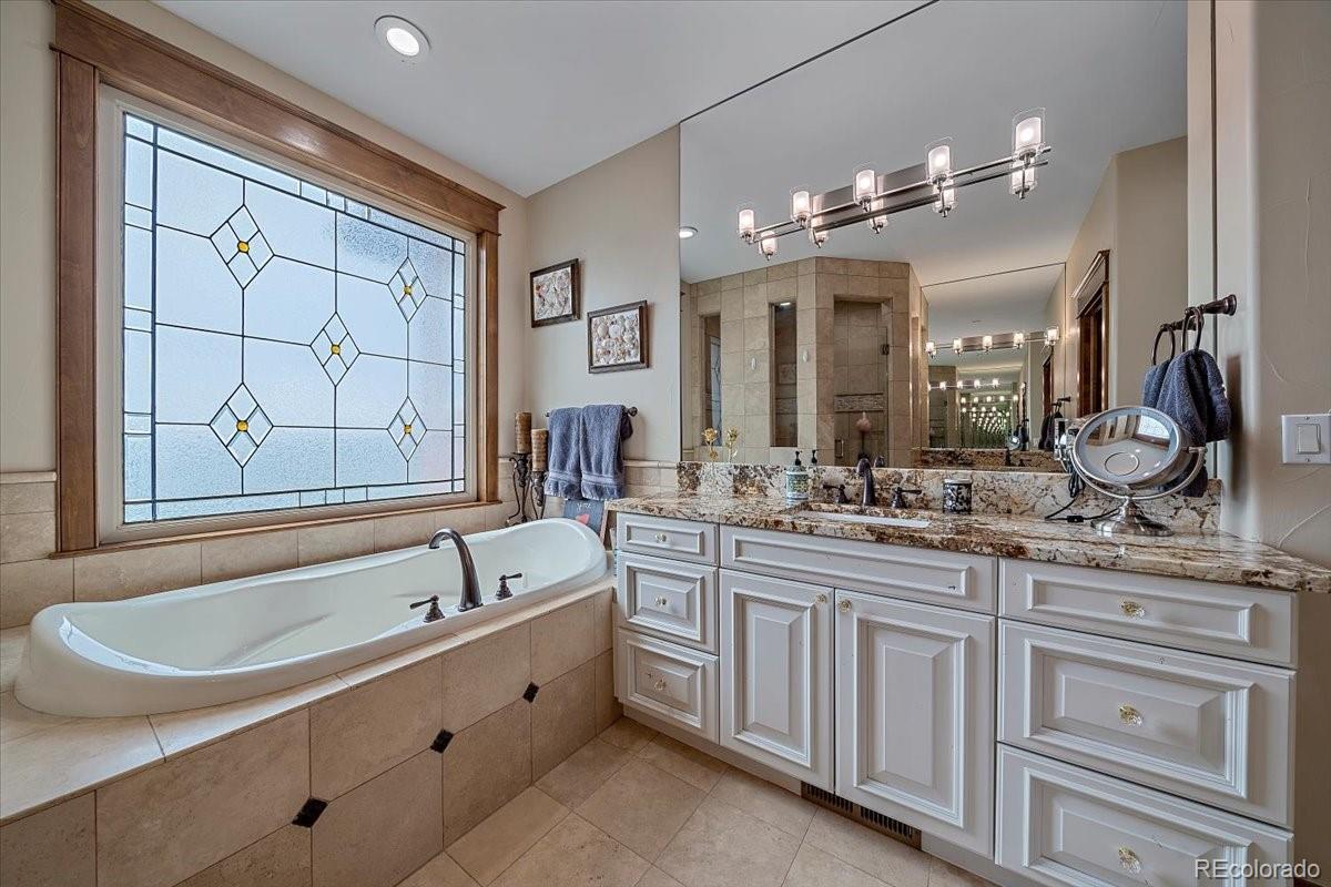 1254 Buffalo Ridge Road Castle Pines, CO 80108 - Photo 19 of 40 a bathroom with a bathtub a double vanity sink a vanity a window and a mirror