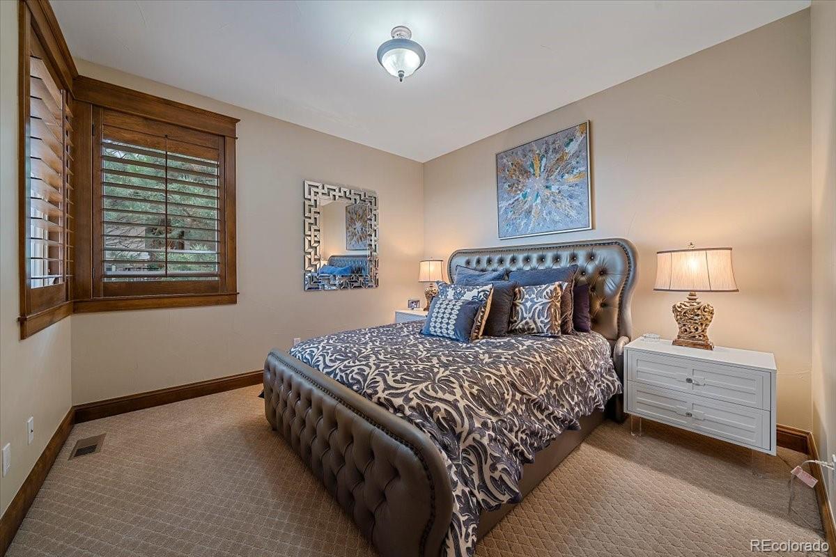 1254 Buffalo Ridge Road Castle Pines, CO 80108 - Photo 21 of 40 a bedroom with a bed and a lamp on dresser