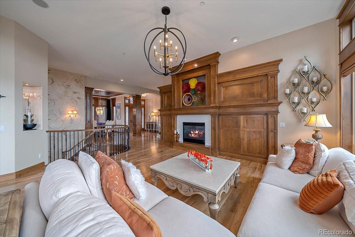 1254 Buffalo Ridge Road Castle Pines, CO 80108 - Photo 9 of 40 a living room with furniture a chandelier a fireplace and a large mirror