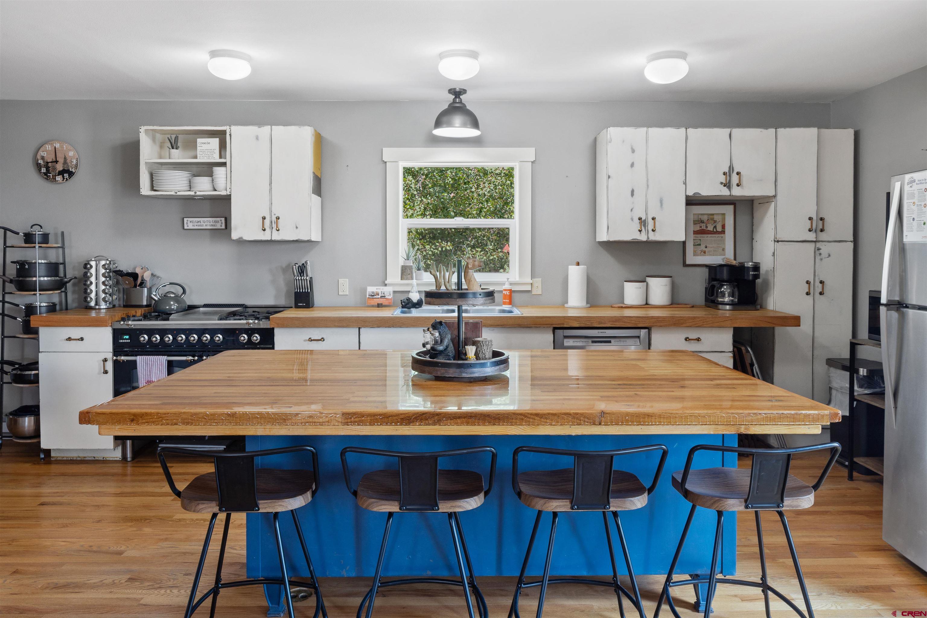 301 West 3rd Street Creede, CO 81130 - Photo 7 of 28 a kitchen with stainless steel appliances a table chairs and a refrigerator