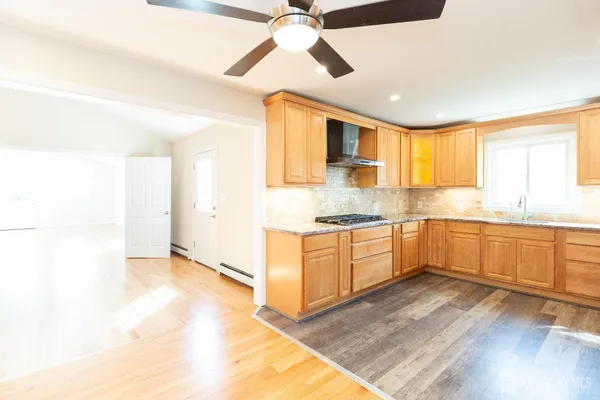 a kitchen with granite countertop stainless steel appliances a refrigerator cabinets and wooden floor