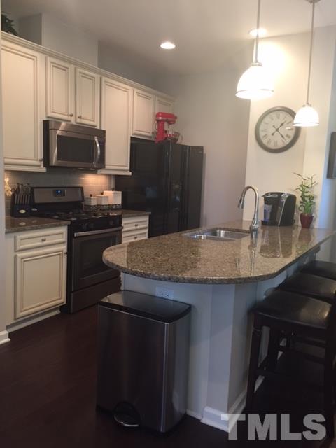 738 Wickham Ridge Road Apex, NC 27539 - Photo 2 of 23 a kitchen with granite countertop a sink a stove top oven and refrigerator