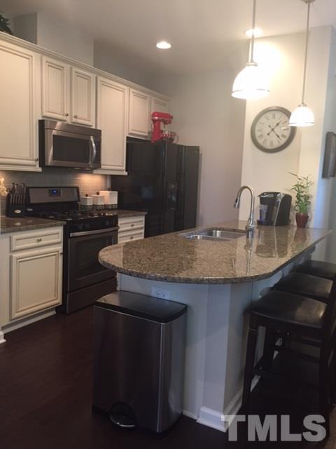 738 Wickham Ridge Road Apex, NC 27539 - Photo 4 of 23 a kitchen with kitchen island granite countertop stainless steel appliances a stove a sink a microwave oven with cabinets and wooden floor
