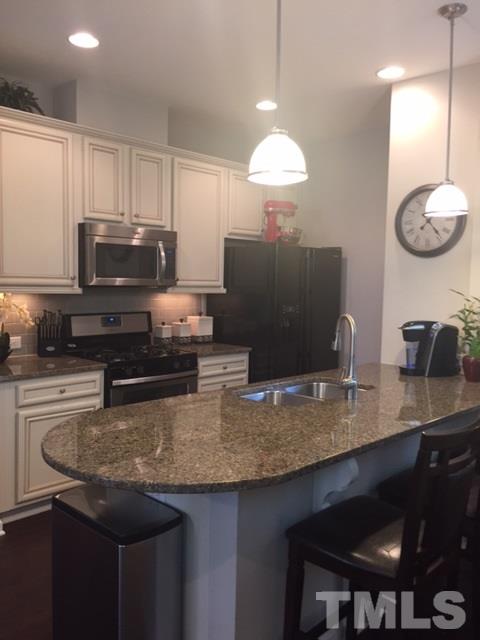 738 Wickham Ridge Road Apex, NC 27539 - Photo 6 of 23 a kitchen with granite countertop a sink a counter top space cabinets and stainless steel appliances