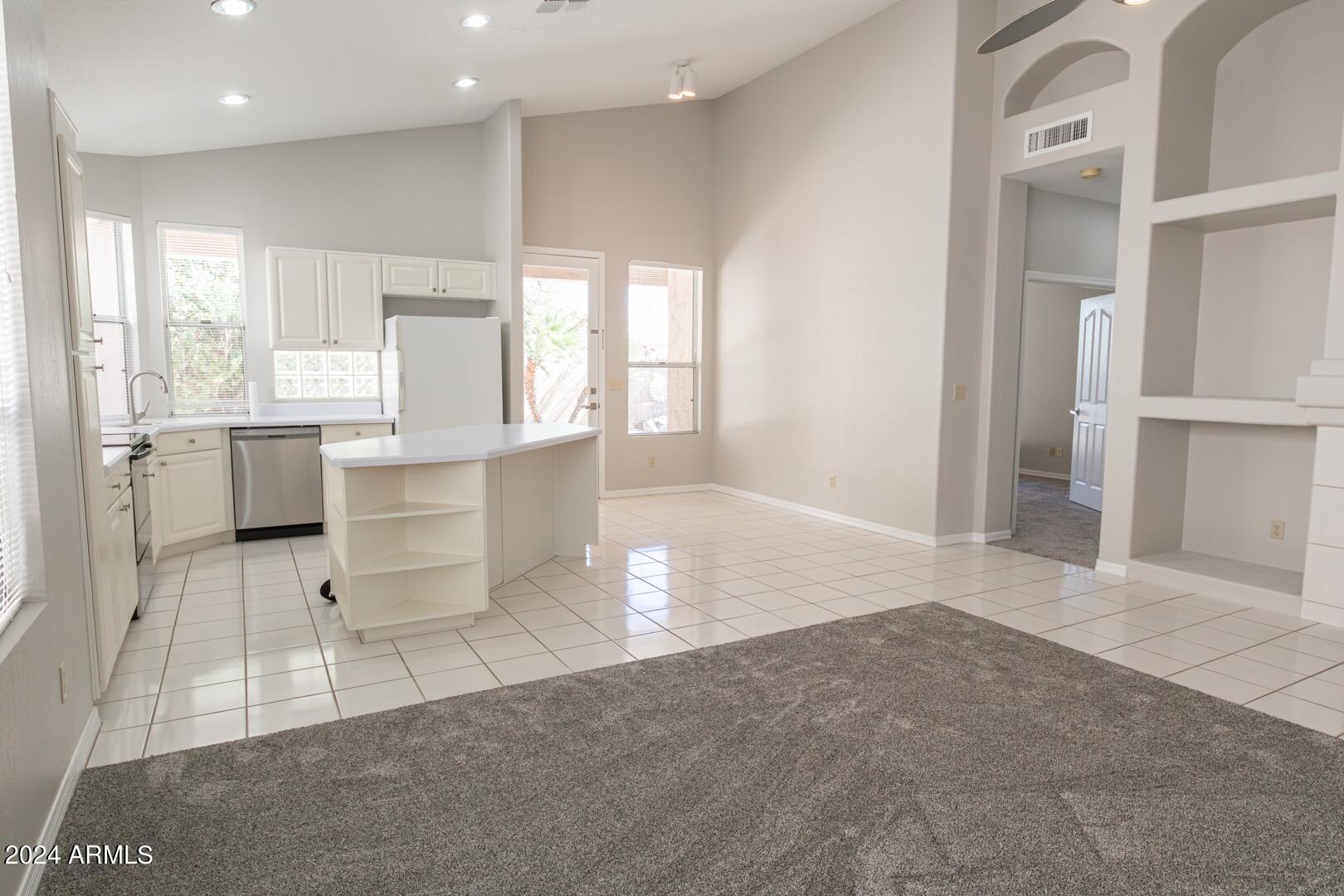 16051 South 24th Place Phoenix, AZ 85048 - Photo 13 of 42 a large white kitchen with kitchen island a sink a stove a refrigerator and white cabinets next to a window