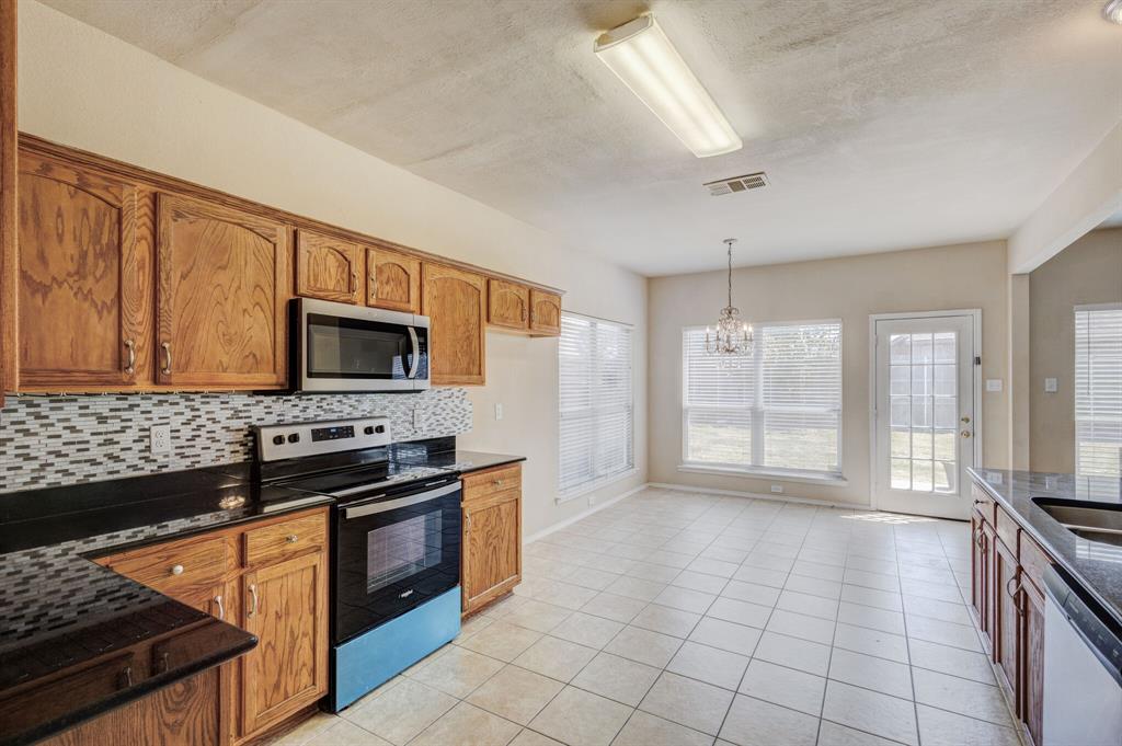 7310 Northpoint Drive Rowlett, TX 75089 - Photo 24 of 32 a kitchen with stainless steel appliances a stove a sink and a microwave