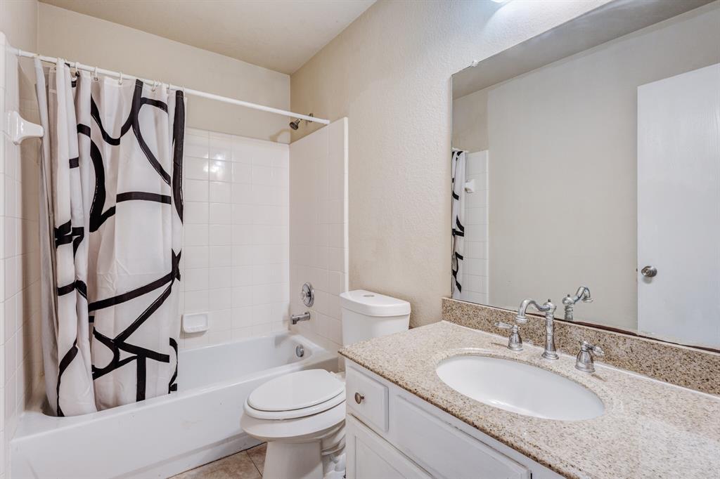 7310 Northpoint Drive Rowlett, TX 75089 - Photo 29 of 32 a bathroom with a granite countertop sink toilet and a mirror