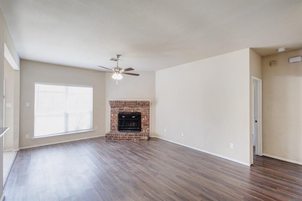 7310 Northpoint Drive Rowlett, TX 75089 - Photo 8 of 32 an empty room with wooden floor fireplace and ceiling fan