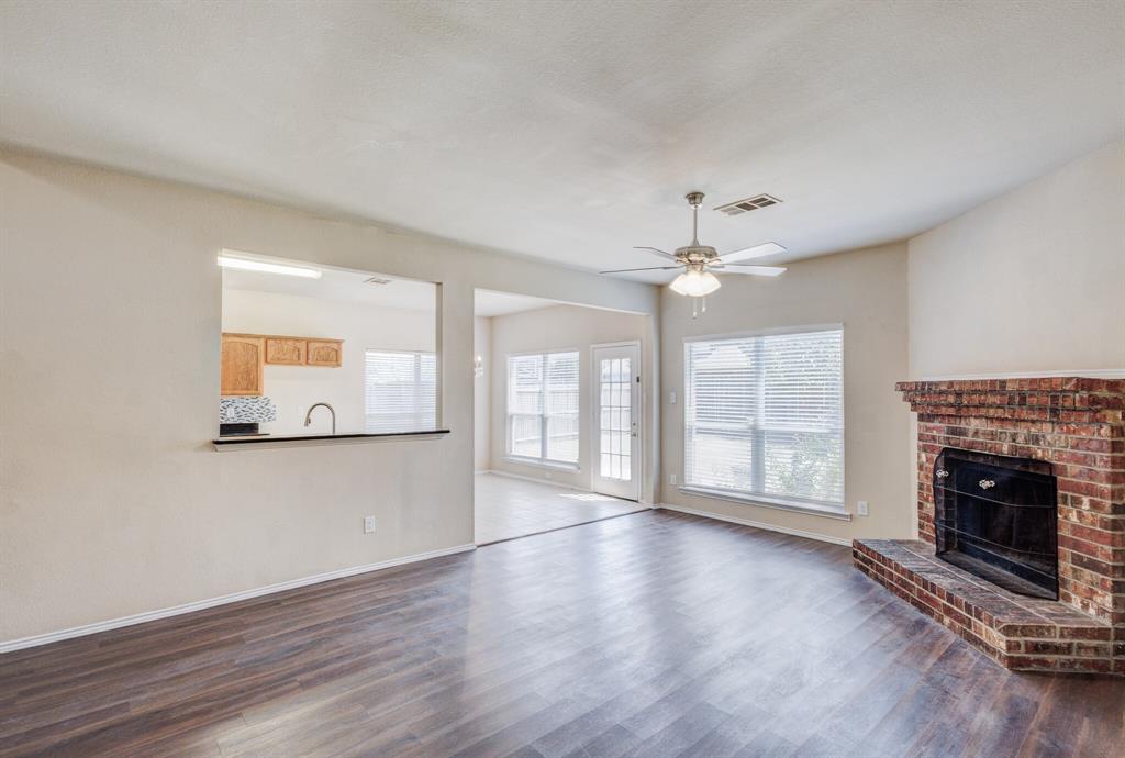 7310 Northpoint Drive Rowlett, TX 75089 - Photo 9 of 32 an empty room with wooden floor fireplace and windows