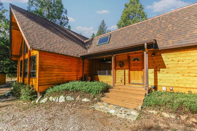 a backyard of a house with large trees and wooden fence