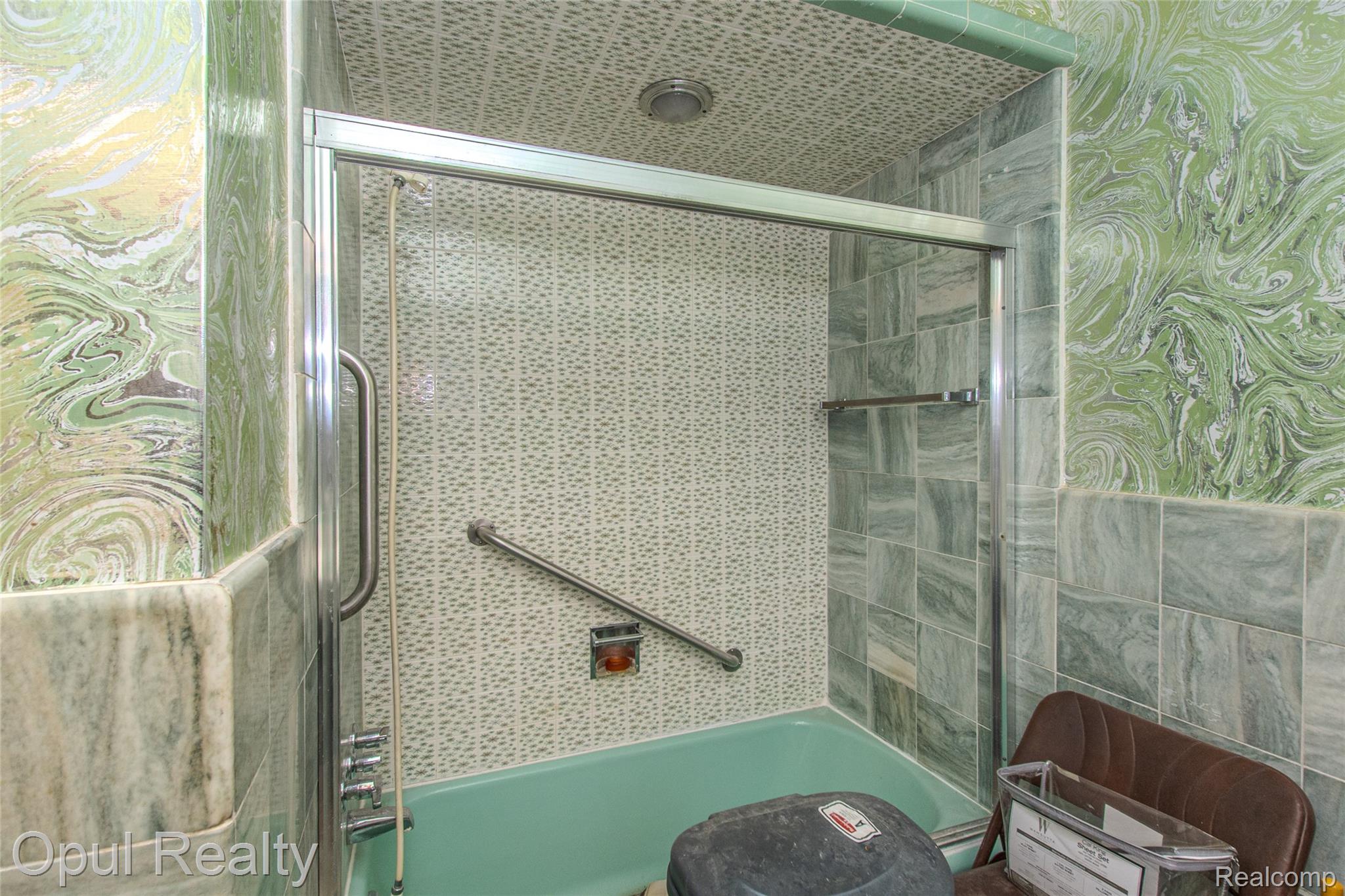 6455 Norham Road Bloomfield Hills, MI 48301 - Photo 54 of 93 Bathtub with a sliding glass enclosure, accented by green-toned patterned wall tiles and a textured ceiling