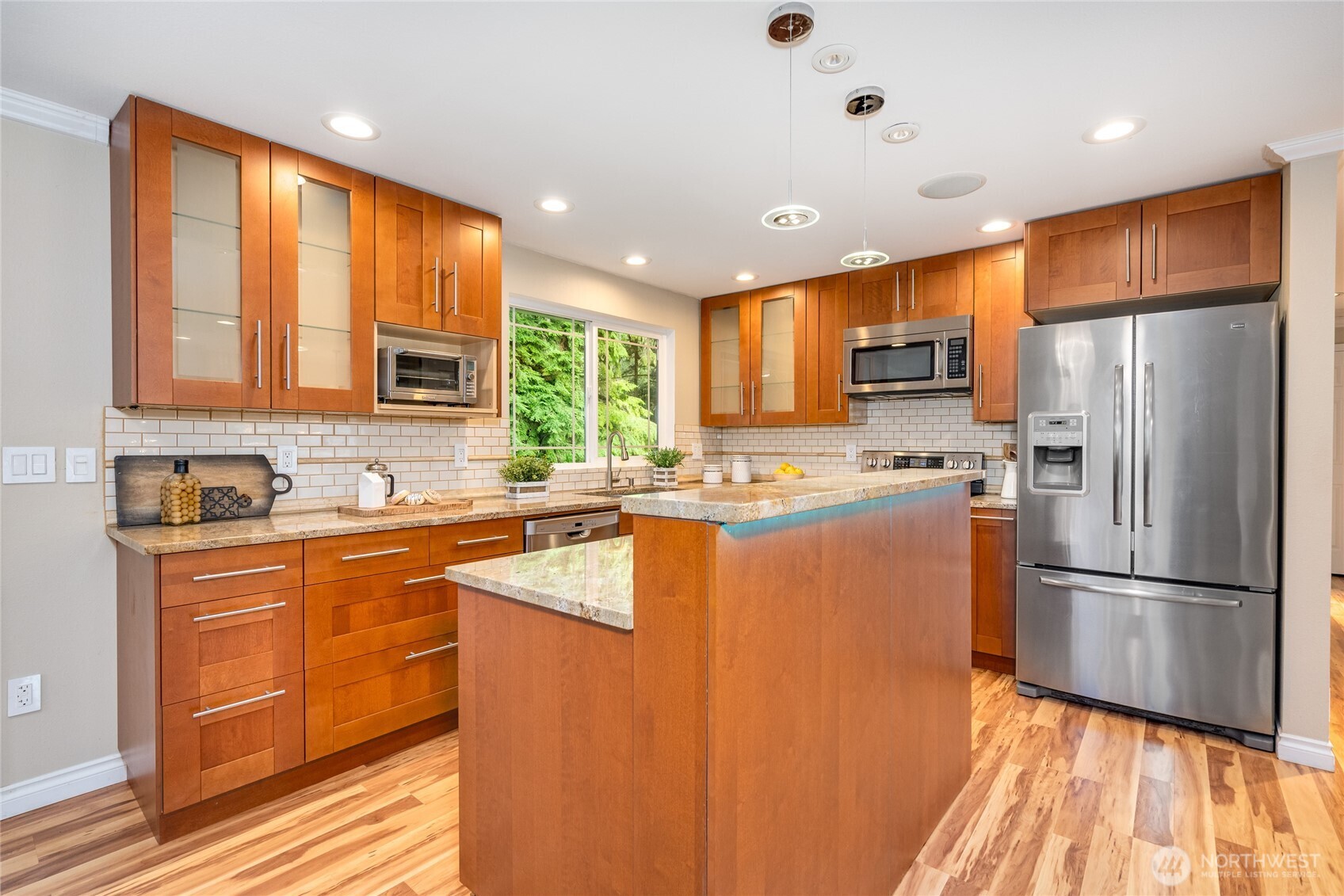 3113 198th Place Southeast Bothell, WA 98012 - Photo 6 of 32 a kitchen with kitchen island granite countertop wooden floors stainless steel appliances a sink and a window