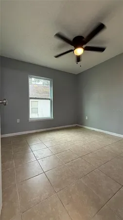 an empty room with windows and ceiling fan