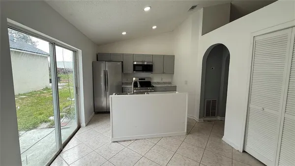 a living room with stainless steel appliances granite countertop a refrigerator and a sink