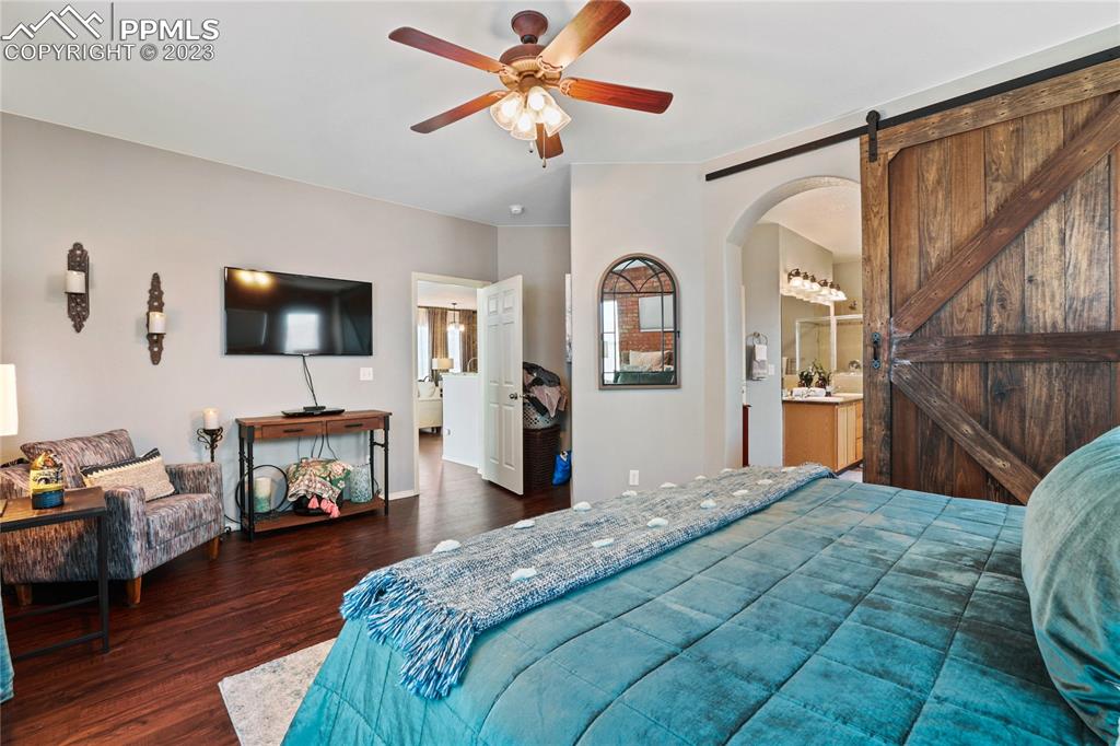 6435 Coyote Ridge Court Colorado Springs, CO 80923 - Photo 25 of 50 a bedroom with a bed a flat screen tv and a chandelier