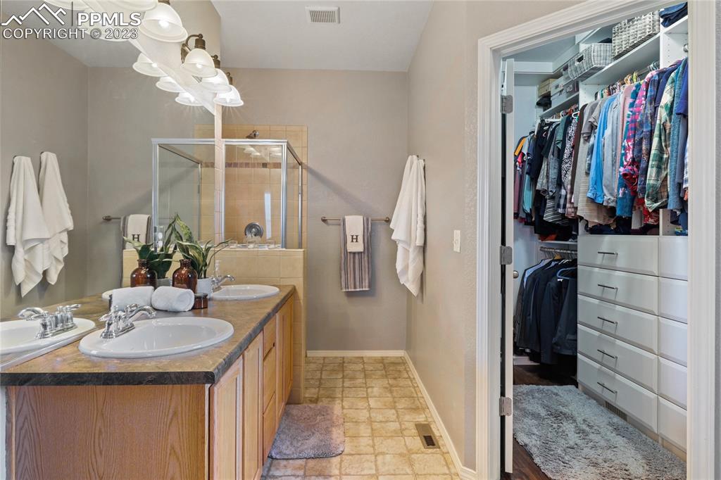 6435 Coyote Ridge Court Colorado Springs, CO 80923 - Photo 26 of 50 a bathroom with a sink a mirror and shower