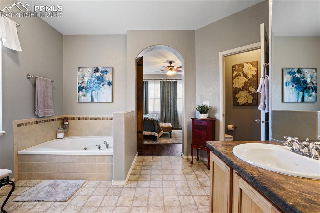 6435 Coyote Ridge Court Colorado Springs, CO 80923 - Photo 30 of 50 a bathroom with a tub sink and mirror