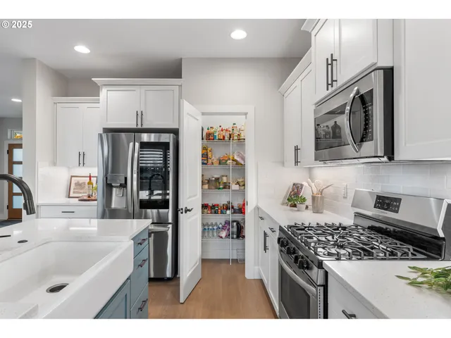 a kitchen with stainless steel appliances granite countertop a sink stove refrigerator and cabinets